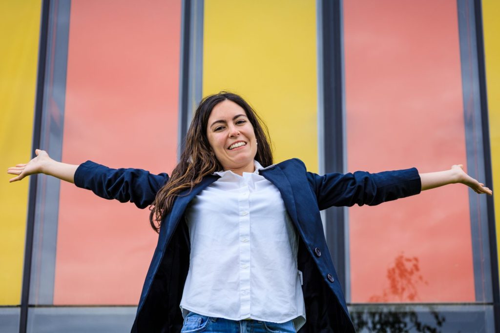 Businesswoman opening arms over red and yellow background.